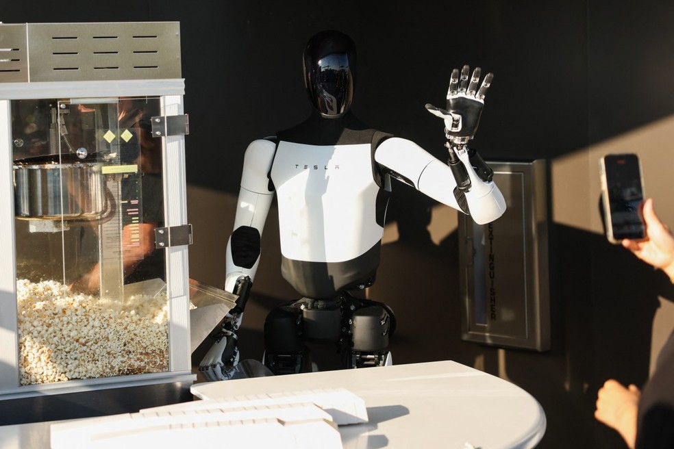 Um robô Tesla Optimus pega pipoca e acena para os participantes durante a inauguração do restaurante Tesla Diner and Drive-In — Foto: Patrick T. Fallon / AFP