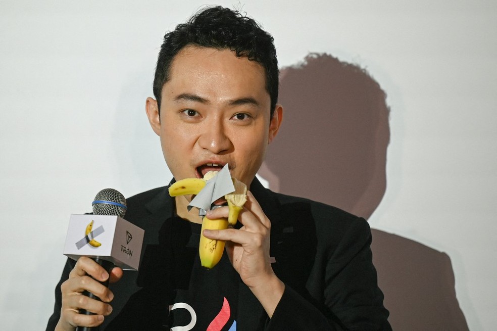 Bilionário Justin Sun come banana de obra de arte polêmica que ele comprou por US$ 6，2 milhões， em Hong Kong， em 29 de novembro de 2024. — Foto: Peter Parks/ AFP