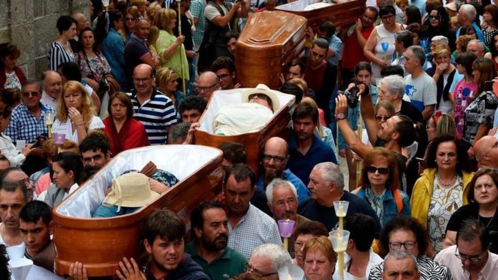 Pessoas levam nos ombros caixões com pessoas vivas no seu interior， durante a procissão de Santa Marta de Ribarteme， em 2019 — Foto: Miguel Riopa/AFP via Getty Images/BBC
