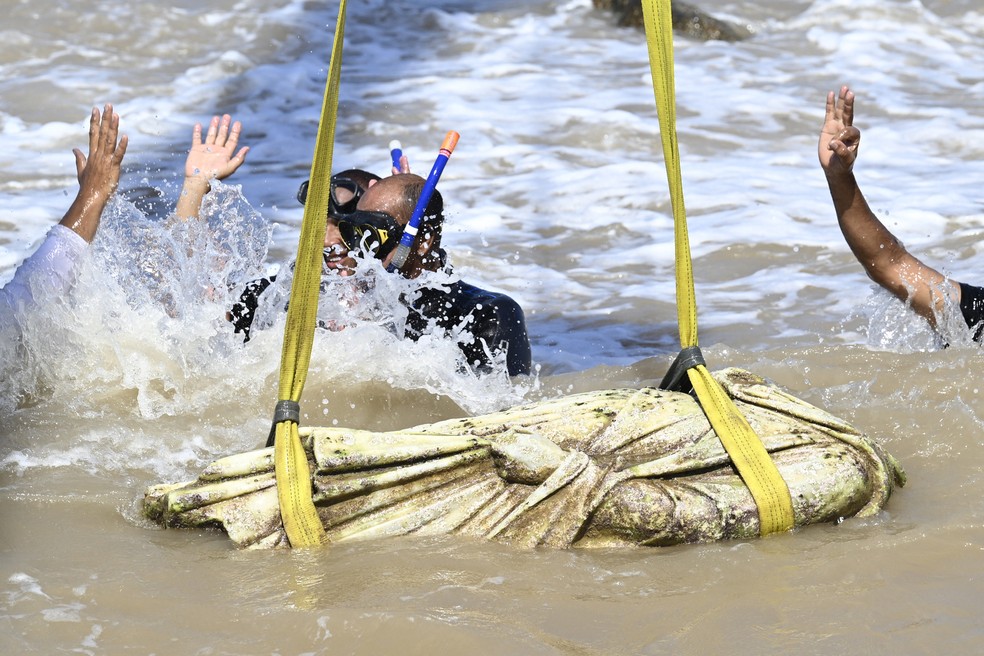 Mergulhadores comemoram enquanto um guindaste puxa um artefato das águas da baía de Abu Qir， em Alexandria， no dia 21 de agosto de 2025， como parte de um evento organizado pelo Ministério do Turismo e das Antiguidades para recuperar antiguidades submersas. — Foto: Khaled DESOUKI / AFP